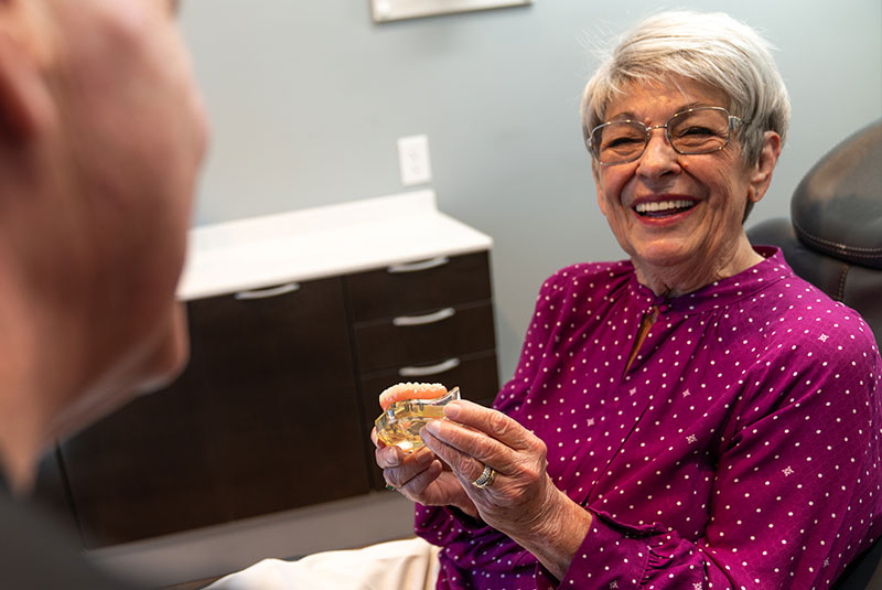patient holding dental implant model within the dental center